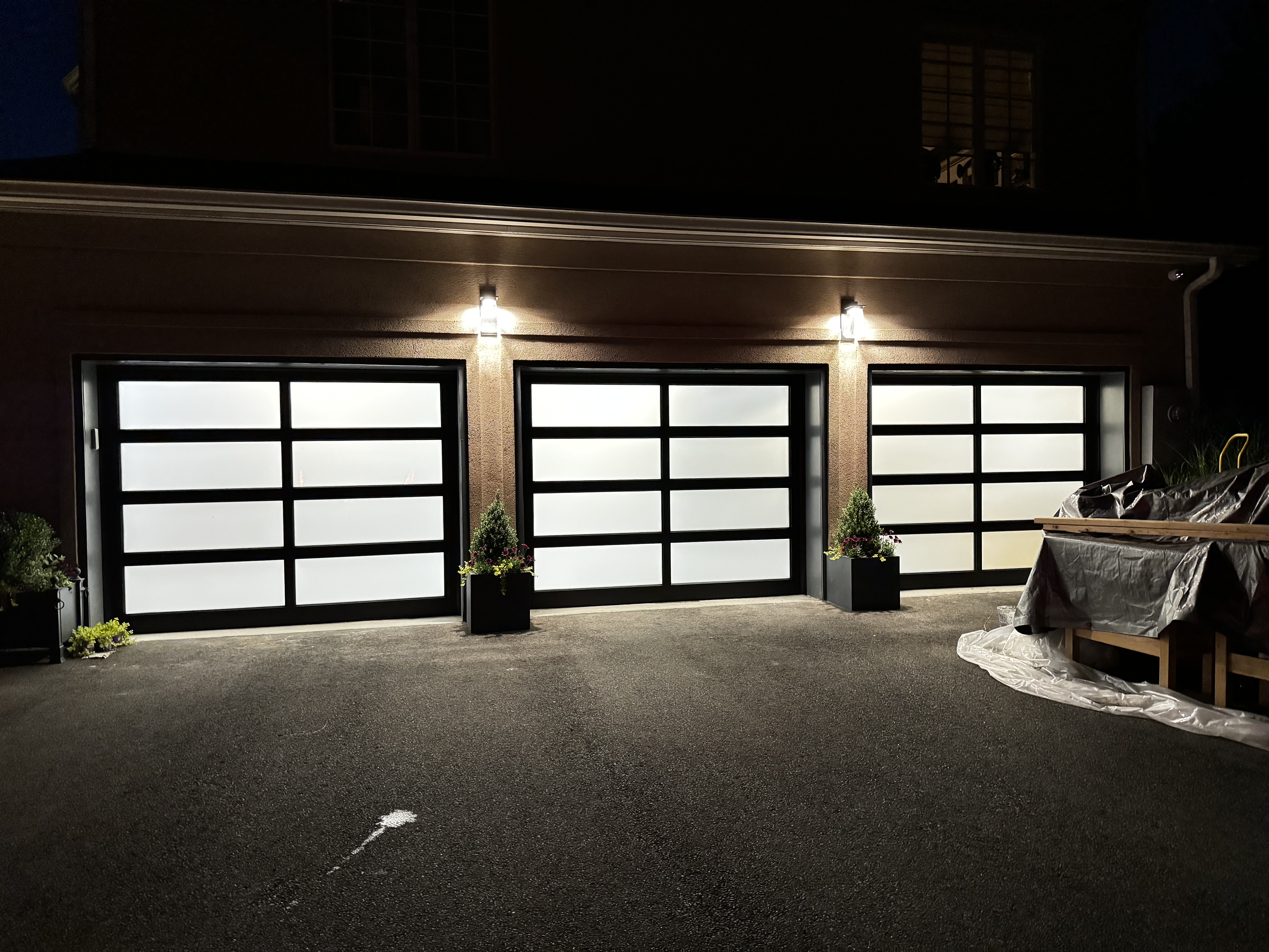 Modern black aluminum glass garage doors — nighttime exterior